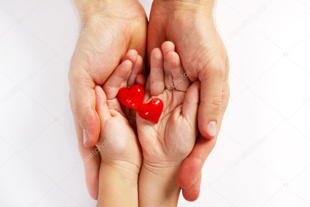 Man's and baby's hands holding two red hearts
