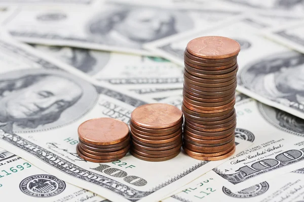 Stack US pennies in an ascending bar graph on background with money american hundred dollar bills — Stock Photo, Image