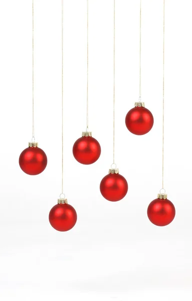 Boules de Noël rouge mat accrochées à des cordes dorées sur fond blanc — Photo