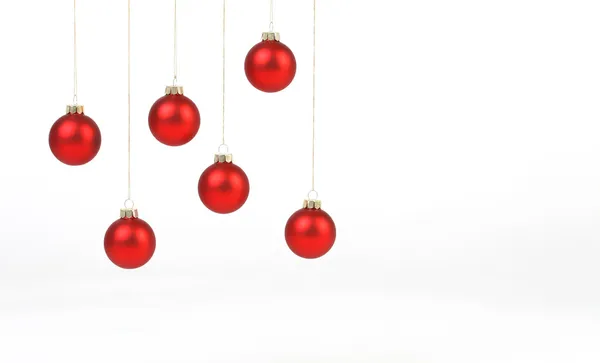 Palle di Natale rosso opaco appeso su corde d'oro su sfondo bianco — Foto Stock