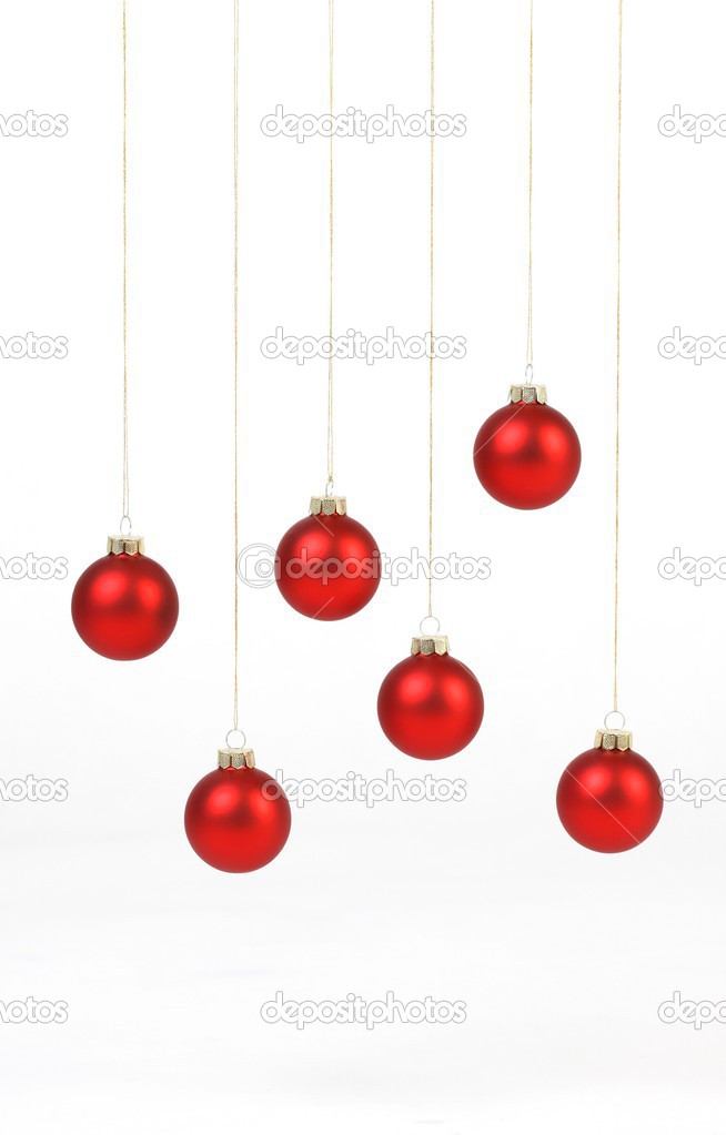 Red matt christmas balls hanging on golden strings on white background