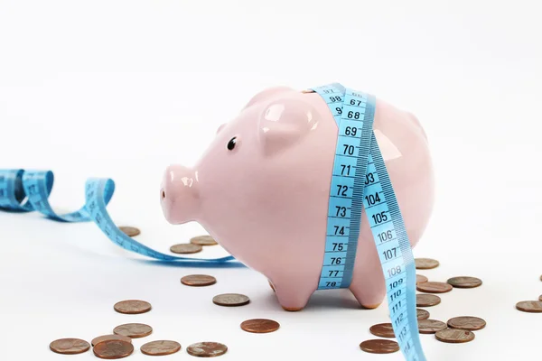 Pink piggy bank with measuring-tape and around a lot pennies on white background — Stock Photo, Image