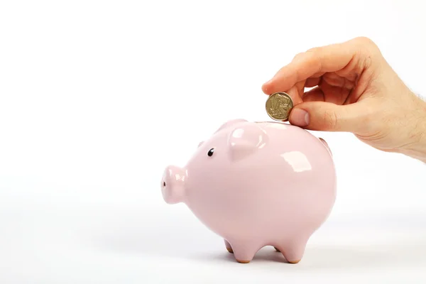 Piggy bank style money box with one old crown falling into slot on white background — Stock Photo, Image