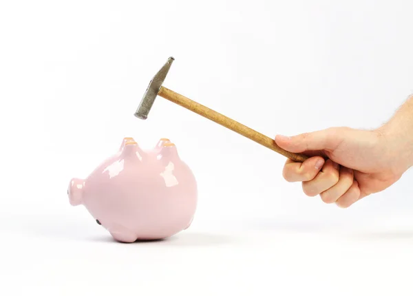 A hand holding a hammer which is raised above a upside down pink piggy bank — Stock Photo, Image