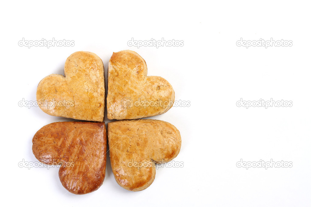 Four-leaf clover of gingerbread composed of four gingerbread hearts on white background