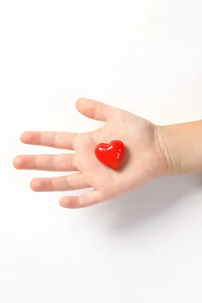 Corazón rojo en la mano de los niños sobre fondo blanco. Corazones en la palma - símbolo del amor —  Fotos de Stock