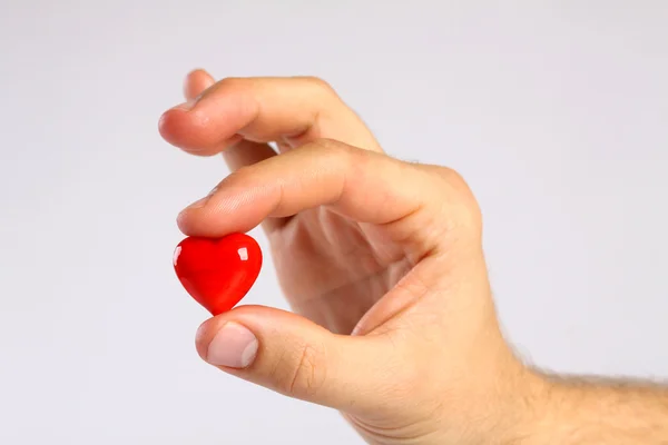 Corazón rojo en los dedos del hombre sobre fondo blanco —  Fotos de Stock