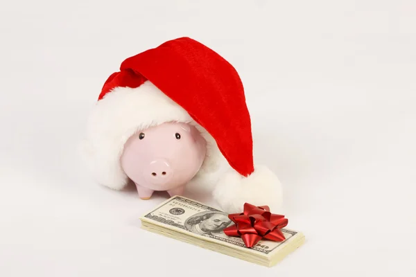 Rosafarbenes Sparschwein mit Weihnachtsmann-Hut und einem Stapel amerikanischer Hundert-Dollar-Scheine mit roter Schleife auf weißem Hintergrund — Stockfoto