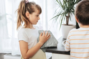 Sevimli beyaz kız ve oğlan mutfak temizliğine yardım ediyor.