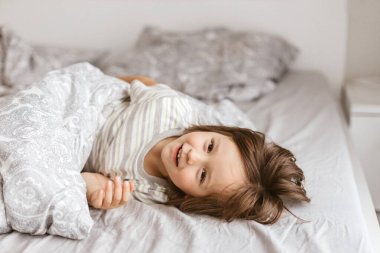 Tatlı çocuk, yeni yürümeye başlayan çocuk yatakta kendini şımartıyor. Mutlu bir çocukluk. Karantina sırasında ebeveynlerle oyunlar. Tatiller evde..