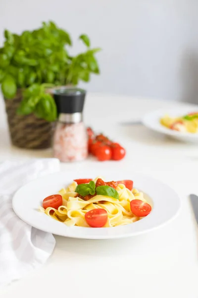 Massa italiana com tomate cereja, molho de tomate e queijo, decorada com um raminho de manjericão. Almoço ou jantar prontos. Definição da tabela — Fotografia de Stock