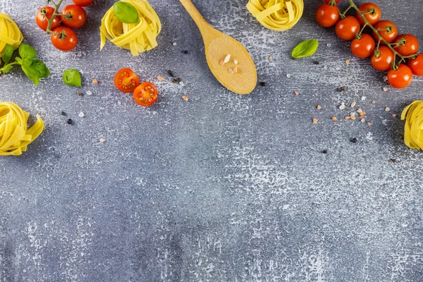 Cocinar pasta italiana. Plano yacía sobre un fondo gris de los ingredientes para la pasta. Espaguetis, tomates cherry, especias y albahaca. Lugar para el texto — Foto de Stock
