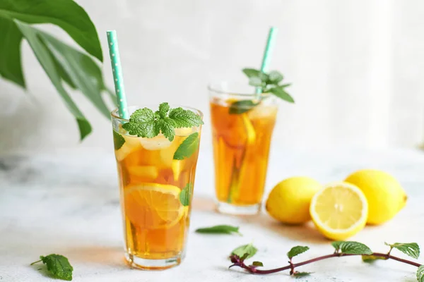 Холодный чай в стакане с соломой, мятным листом и ломтиками лимона внутри. Прохладные напитки в жару — стоковое фото