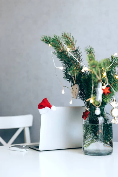 Otevřený notebook na stole vedle vánočního stromku zdobeného míčky a věncem. Nový rok a vánoční nálada na pracovišti — Stock fotografie