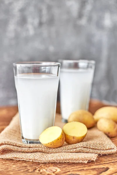 Şeffaf bardakta patates sütü masanın üzerinde patates şişelerinin yanında. Alternatif süt. Gıda trendleri. bitki sütü