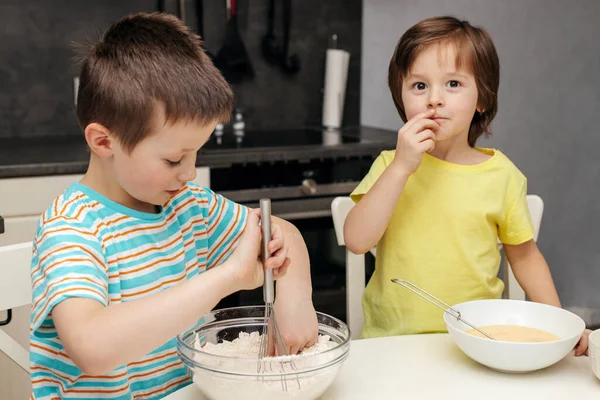Deux frères préparent la pâte à gâteau dans la cuisine à la maison. Du temps avec les enfants à la maison. Des enfants dans la cuisine. Cuisiner avec des enfants. Pâte à pétrir enfants — Photo