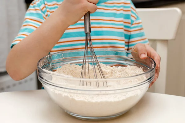 Close-up of a whisk with dough. The boy is kneading the dough for a pie or a cookie. The dough drips off the whisk. — Zdjęcie stockowe