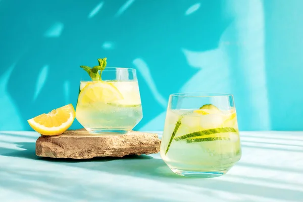 Летний детоксикационный освежающий напиток или алкогольный коктейль с ломтиками лимона и льдом, украшенный веточкой мяты. Холодная вода с лимоном. Здоровые напитки — стоковое фото