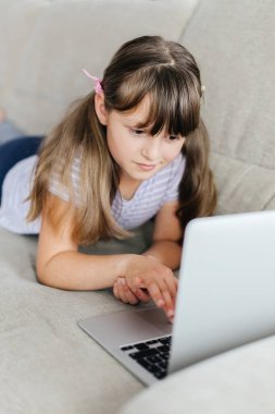 Liseli bir kız uzaktan çalışıyor ve bir dizüstü bilgisayarla öğretmenini arıyor. Evde uzaktan öğrenme. Çocuklar ve modern teknoloji