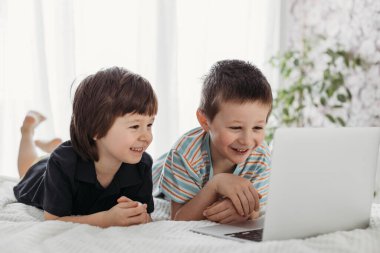 Online eğitim. Çocuklar dizüstü bilgisayardan ders izler. Çocuklar günlük hayatta aletler kullanırlar. Çocuklar ve aletler.