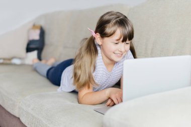 Liseli bir kız uzaktan çalışıyor ve bir dizüstü bilgisayarla öğretmenini arıyor. Evde uzaktan öğrenme. Çocuklar ve modern teknoloji