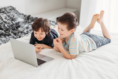 Distance learning at home. Boy schoolboy sits on bed and watches webinar on digital tablet laptop