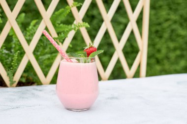 Çilekli muzlu milkshake ya da çilek ve nane yaprağıyla süslenmiş smoothie. Ferahlatıcı yaz meşrubatı. Sağlıklı gıda konsepti