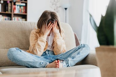 Yorgun liseli kız kanepede oturur ve elleriyle tutunur. Kişi başı. Sınavların stresi ve çalışmanın yorgunluğu. Rahatlama ihtiyacı..