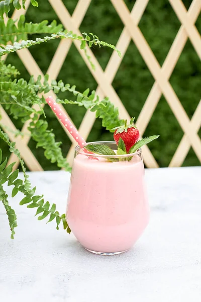 Strawberry banana milkshake or coconut milk smoothie on a garden table. Healthy food and drinks from organic products. Vegetarian diet