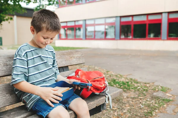 Boy Sits Bench School Yard Takes Out Sandwich Lunch Box — Fotografia de Stock