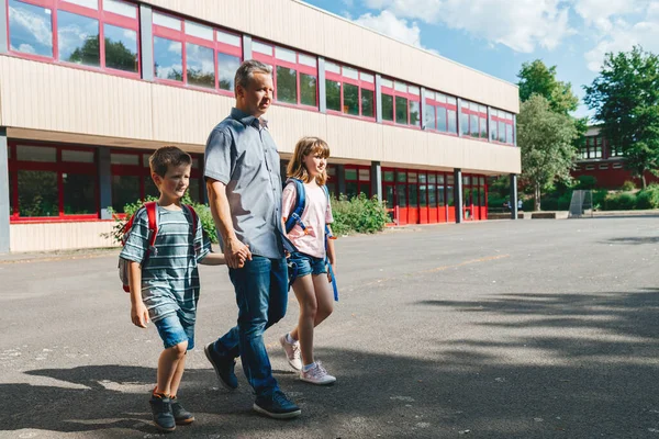 Dad accompanies or picks up children from school. Beginning of the school year, students go back to school.