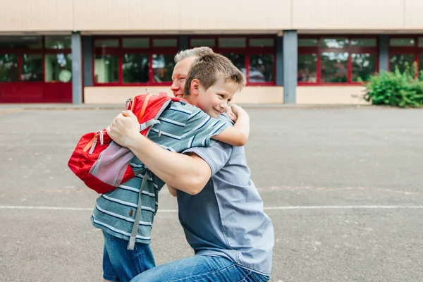 Happy Young Dad Hugging His Schoolboy Son Front School Building — Zdjęcie stockowe