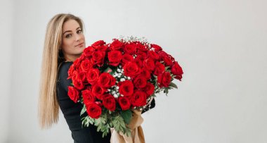 Kocaman bir buket kırmızı gülleri olan çekici genç bir kadın. Doğum günü ya da sevgililer günü hediyesi. Nişan ve aşk belirtileri. 