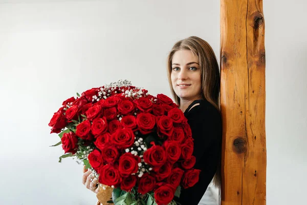 Kocaman bir buket kırmızı gülle büyüleyici bir kız. Kız sevgilisinden aldığı bir hediyeyle mutlu. Nişan ve aşk belirtileri. 