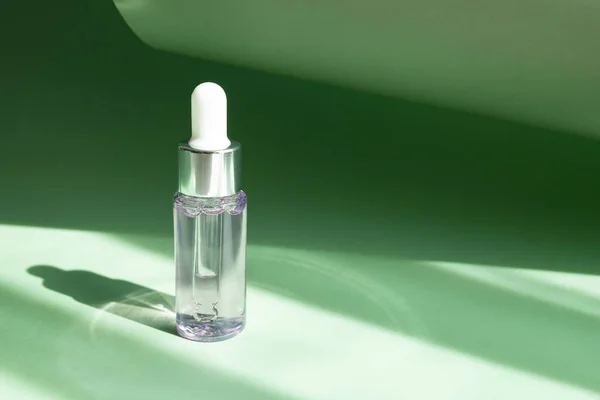 透明的化妆品瓶 在明亮的阳光下 绿色的底色 — 图库照片
