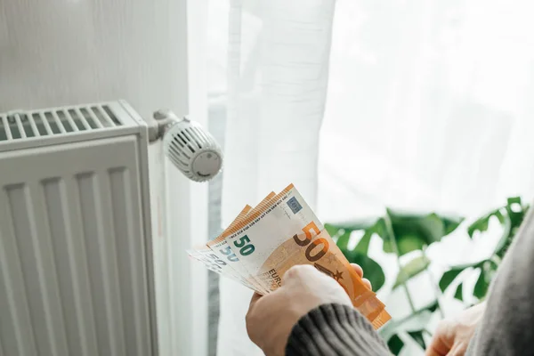 Närbild Mans Händer Med Sedlar Händerna Bredvid Ett Värmeelement Höjda — Stockfoto