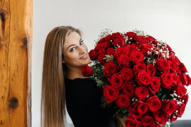 Kocaman bir buket kırmızı gülle genç bir kız. Çiçek kokan mutlu kadın. Tatiller ve doğum günleri için hediyeler. Sevgililer Günü. Çiçek teslimatı.