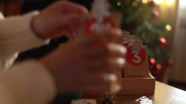 Close-up hands of unrecognizable young woman puts bags of christmas advent calendar in wooden tray on Christmas Eve. — Stock Footage Close-up hands of unrecognizable young woman puts bags of christmas advent calendar in wooden tray on Christmas Eve. Royalty Free Stock Footage