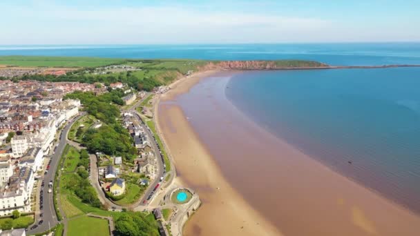 イギリスのフィリーの町のビーチフロントの空中映像は 晴れた夏の日に人々がリラックスしてビーチで楽しんでいることを示しています — ストック動画