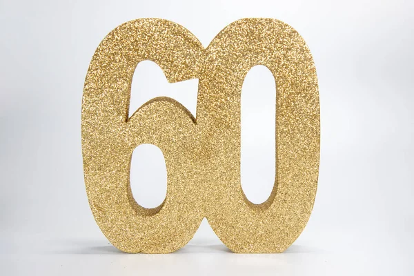 A gold glittery sign that says the number 60 on a white background, 60th birthday or anniversary concept