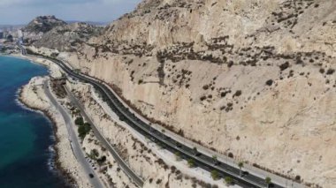 İspanya 'nın Alicante kentindeki çarpıcı plajın hava görüntüleri, güzel bir yaz gününde, sahil boyunca kayalıkları ve yolu gösteren bir drone ile çekildi.