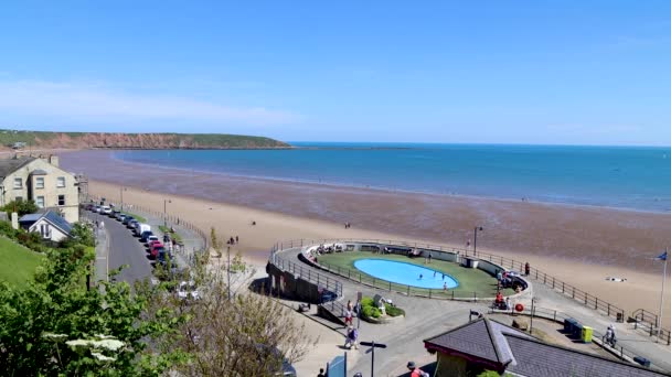 英国のノースヨークシャーのフィリーの海辺の町の映像は 夏の時間にビーチや屋外プールでリラックスして楽しんでいる人々と英国の海辺のビーチを示しています — ストック動画