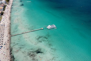 İspanya 'nın Majorca Mallorca adasındaki kumsalın insansız hava aracı fotoğrafı güneşli bir yaz gününde Alcdia köyünün sahilindeki bir tekneyi gösteriyor.