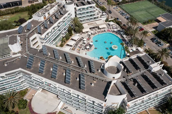 İspanya 'nın güzel Mayorka adasında çekilen hava aracı fotoğrafı çatıda güneş panelleri ve yazın açık yüzme havuzu olan bir otel binasının üst katını gösteriyor.