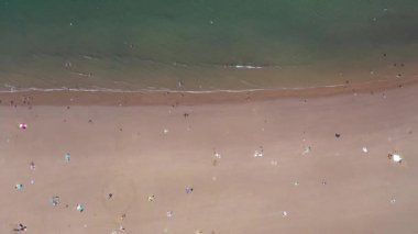 İngiltere, Kuzey Yorkshire 'daki Whitby' nin güzel kumsalının hava görüntüleri sıcak bir yaz gününde kumsalda dinlenen ve oynayan insanların insansız hava aracı görüntülerini gösteriyor.