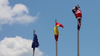 İspanya 'nın İbiza kentinde güneşli bir yaz gününde, İngiliz, İspanyol ve AB bayraklarının üst üste dalgalandığı görüntüler