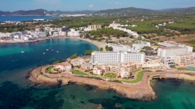 İspanya 'nın güzel İbiza adasının Akdeniz kıyısındaki sahil ve otelleri ve Es Canar köyündeki Playa Es Canar plajını gösteren hava aracı görüntüleri.