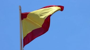 İspanya 'nın İbiza kentindeki mavi gökyüzü ile güneşli bir yaz gününde rüzgarda dalgalanan İspanyol bayrağının görüntüsü.