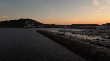 İspanya 'nın güzel İbiza kasabasının hava görüntüleri gün batımında Santa Eularia des Riu' daki kayık limanı boyunca dağların ardında batan güneşi gösteriyor.