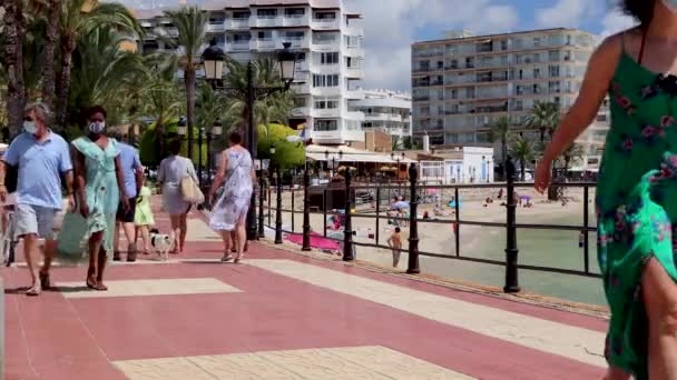 イビサ島スペイン 2020年7月19日 明るい晴れた夏の日にスペインのイビザの町のビーチフロントでコロナウイルスCovid 10パンデミック発生のためにマスクを身に着けている人々の映像 — ストック動画